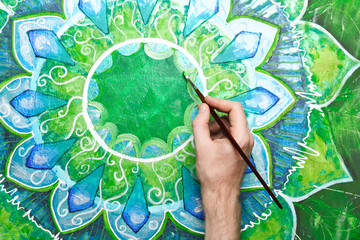 man painting bright green picture with circle pattern, mandala o