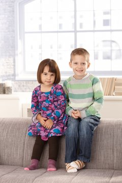 Smiling children sitting on sofa
