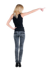 Beautiful young woman pointing at wall. Rear view.