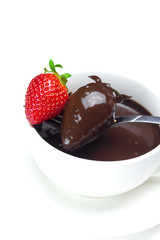 melted chocolate in a cup, fork and strawberries isolated on whi