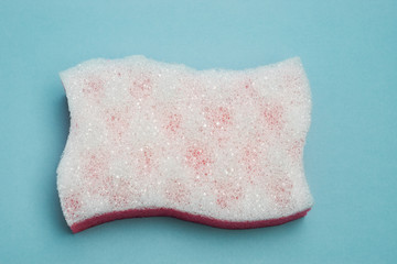 White porous bath sponge in shape of flag on blue background