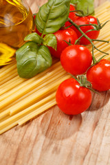 pasta, olive oil and tomatoes on the wood background