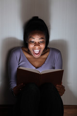 Young girl screams reading a spooky story book