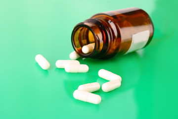 Pill bottle with white pills on green