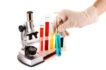 Laboratory metal microscope and test tube in hand with liquid is