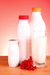 glass of milk and bottle on red background