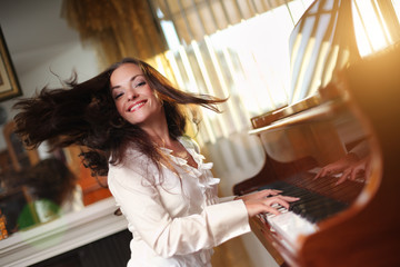 Pianist. Happy young woman playing piano indoors.