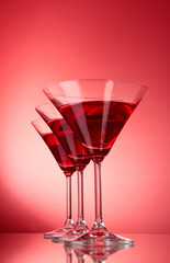 three glasses with martini on red background