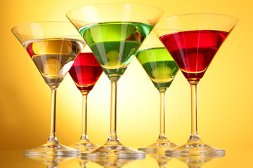 a few glasses of alcoholic drinks in a yellow-brown background