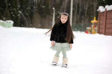 Fototapeta na wymiar Adorable little girl in green tutu dances outside in snow