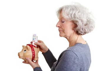 Seniorin steckt Geld in Sparschwein