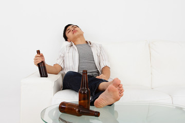 Drunk man on a sofa with beer bottles