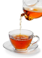 Tea being poured into glass tea cup isolated on a white backgrou