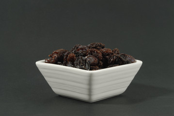 Uvas pasas en cuenco sobre fondo negro