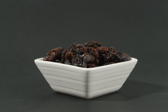 Uvas pasas en cuenco sobre fondo negro