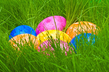 farbige Ostereier mit Tautropfen versteckt im Gras