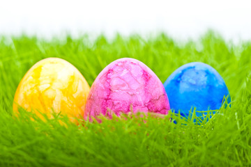 farbige Ostereier im Gras vor hellem Hintergrund