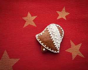 dekoriertes Glöckchen aus Lebkuchen auf rotem Untergrund