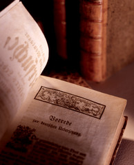 aufgeschlagenes altes Buch mit anderen historischen B&uuml;chern im H