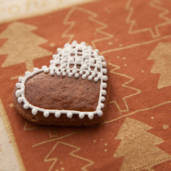 dekoriertes Herz aus Lebkuchen auf weihnachtlichem Untergrund