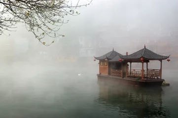 Fotobehang China landscape of boat on foggy river © raywoo
