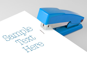 blue stapler lies on a white background - obrazy, fototapety, plakaty