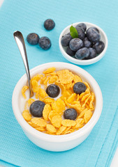 bowl of cornflakes with milk and blueberries