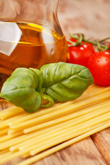 pasta, olive oil and tomatoes on the wood background