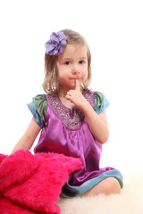 Obraz na płótnie Canvas Little blond girl sitting on a fluffy carpet with pink fur coat
