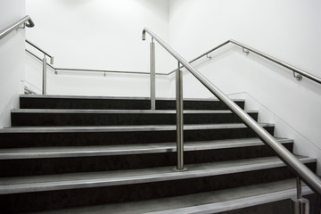 wide staircase with chrome handrails and gray steps, white walls