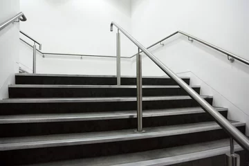 Deurstickers Trappen brede trap met chromen leuningen en grijze treden, witte muren