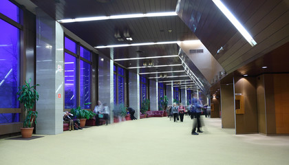 many people sitting, standing and walking in big light lobby