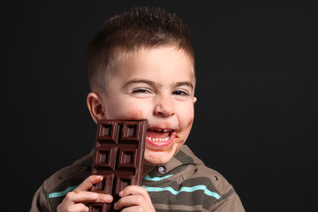 bambino goloso mangia tavoletta di cioccolata - obrazy, fototapety, plakaty