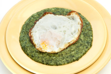 Spinach cream soup with egg in yellow plate