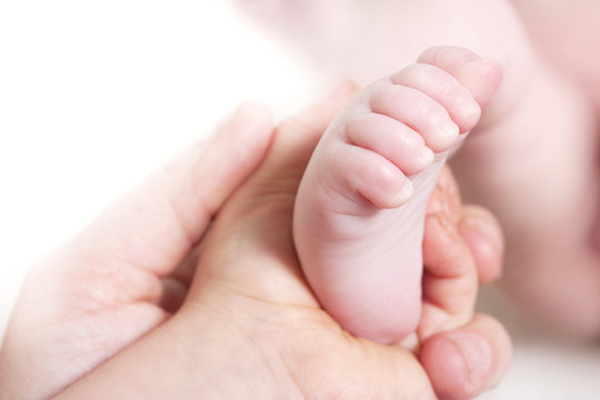 child and mothers hand holding babys foot