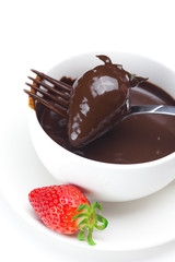 melted chocolate in a cup, fork and strawberries isolated on whi