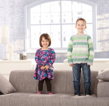 Laughing kids standing on couch