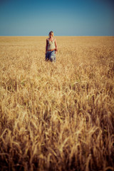Naklejka na ściany i meble Image of young woman on wheat field