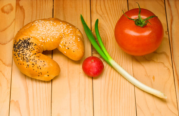 Bun and vegetables isolated on wooden background