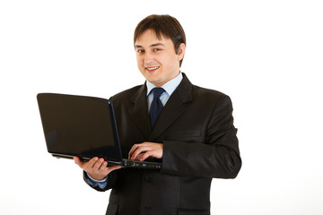 Smiling modern businessman using laptop isolated on white.