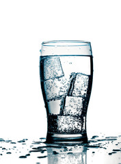 glass with cold purified water and ice, over white background