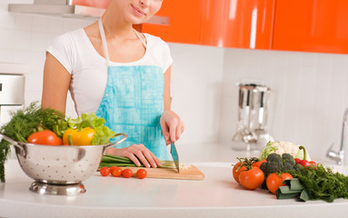 Woman cutting vegetables in modern kitchen interior