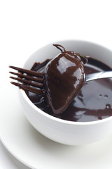 melted chocolate in a cup, fork and strawberries isolated on whi