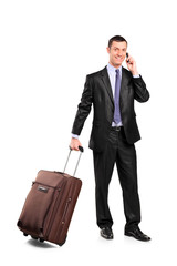 Businessman carrying a suitcase and talking on a cell phone