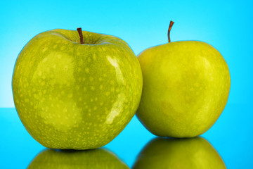 Two green apples on blue background