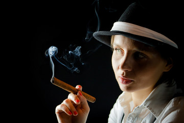 Fototapeta premium Woman in black hat with cigar