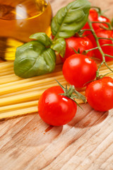 pasta, olive oil and tomatoes on the wood background