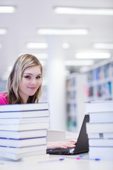 Obraz premium in the library - pretty, female student with laptop and books