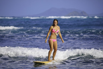 Fototapeta premium teenage girl in pink bikini surfing in hawaii