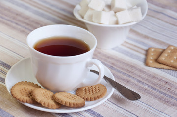 A cup of tea with biscuits and slices of sugar